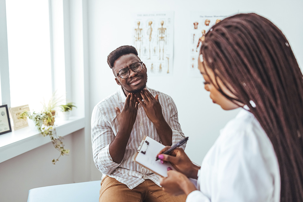 African american mid adult man with eyes closed touching painful throat against white background. copy space, throat, thyroid, medical, pain, sickness and healthcare concept. Shot of a doctor examining a mans throat during a consultation