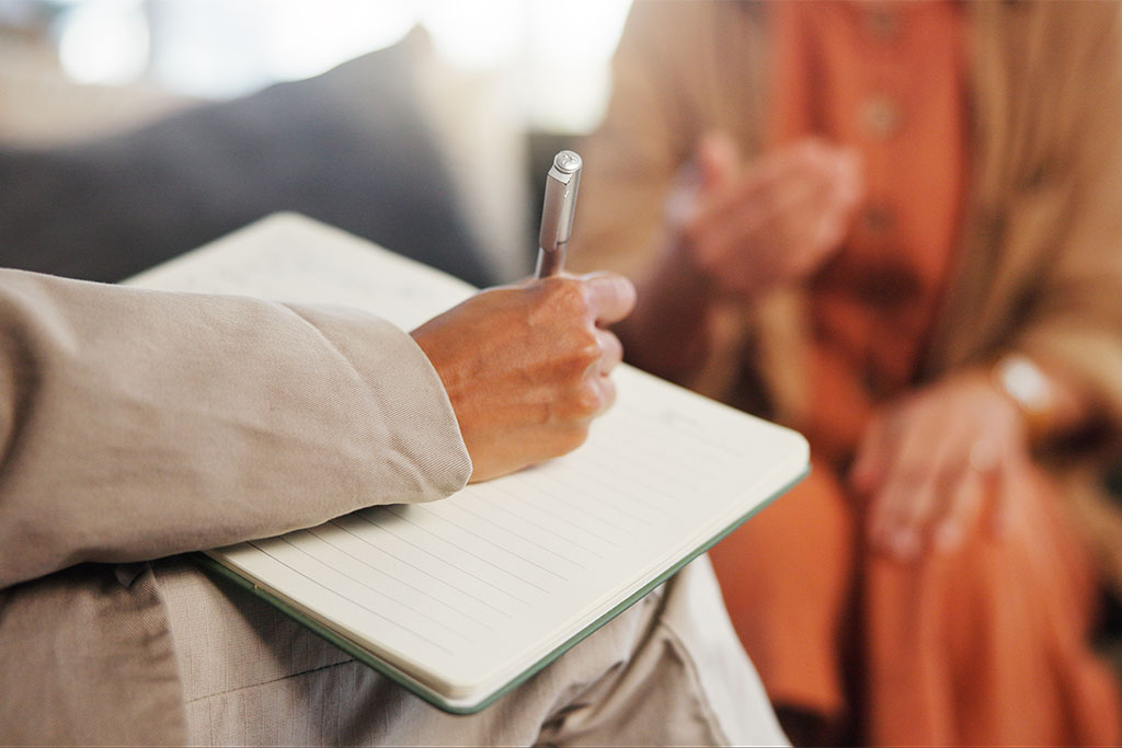 A behavioral services specialist writing notes in a session with a patient.