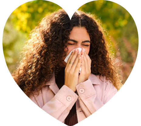 Young Caucasian woman with curly hair blowing your nose in a tissue at street.