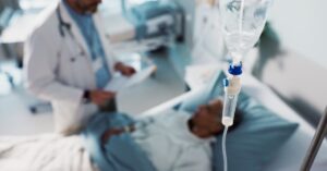 A medical professional adjusting an IV drip for a patient in a healthcare setting, illustrating hydration and treatment services at AllCare.