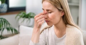 Woman with headache touching her nose bridge and feeling tired
