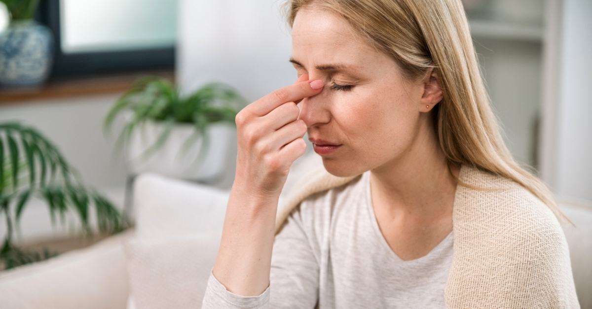 Woman with headache touching her nose bridge and feeling tired